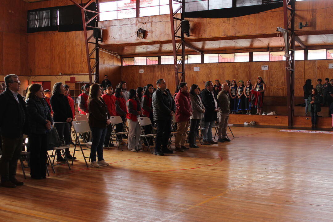 Vista amplia del gimnasio escolar con apoderados y estudiantes reunidos durante un acto comunitario