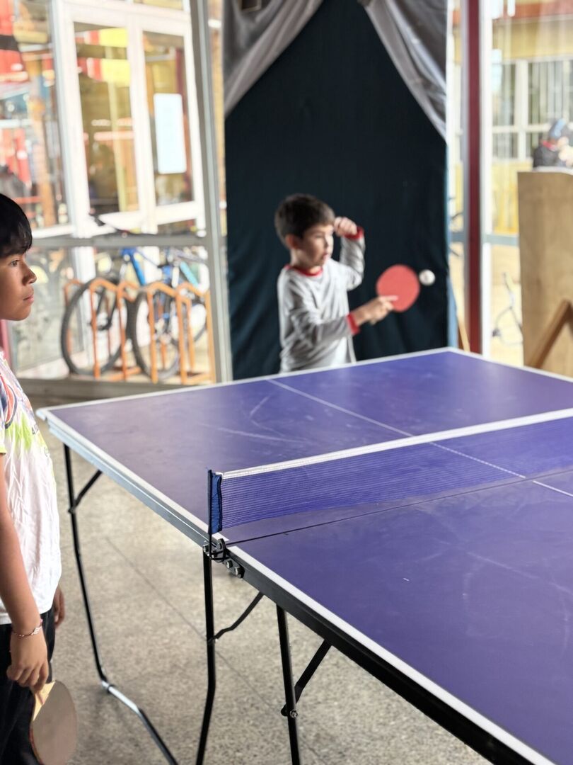 Estudiante en plena acción jugando ping pong en una pausa escolar