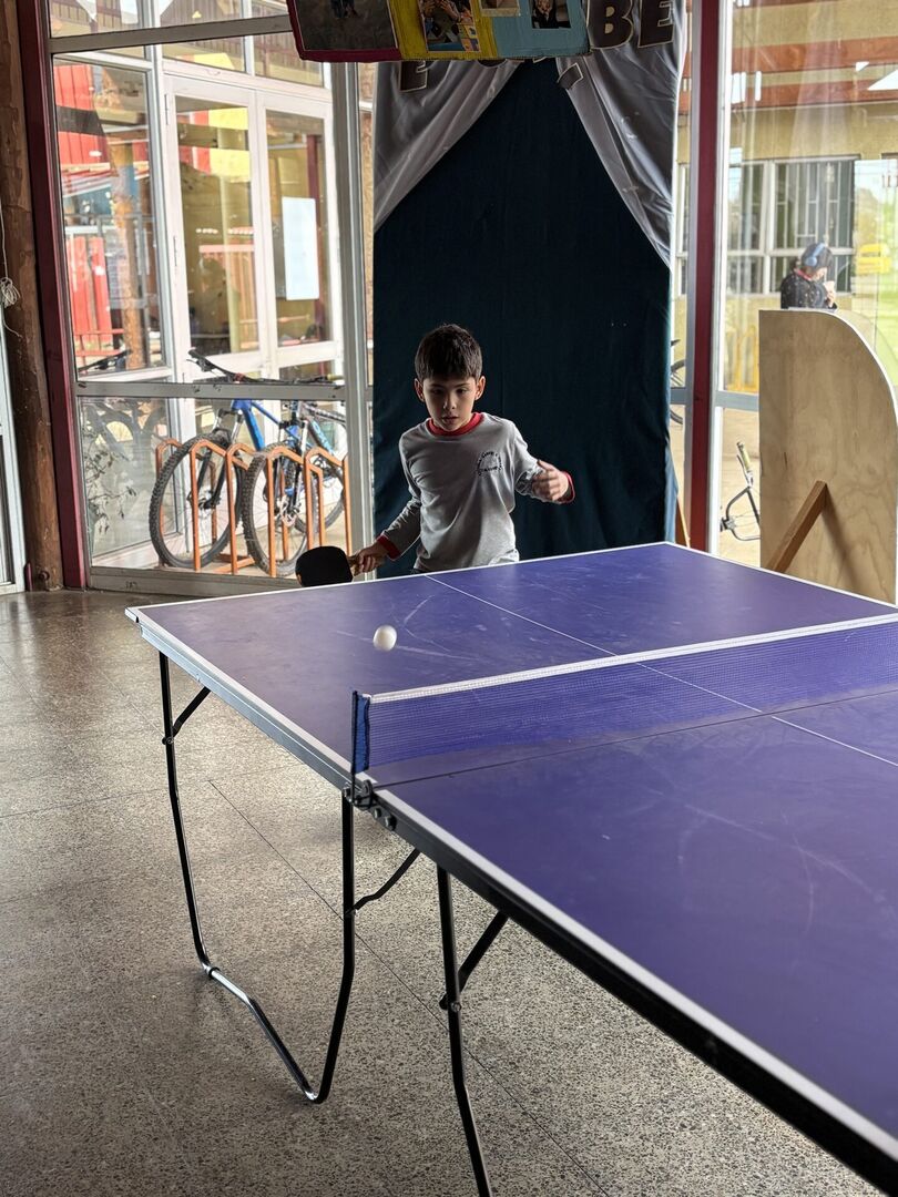 Niño impulsando la pelota con una paleta mientras otro estudiante observa el juego